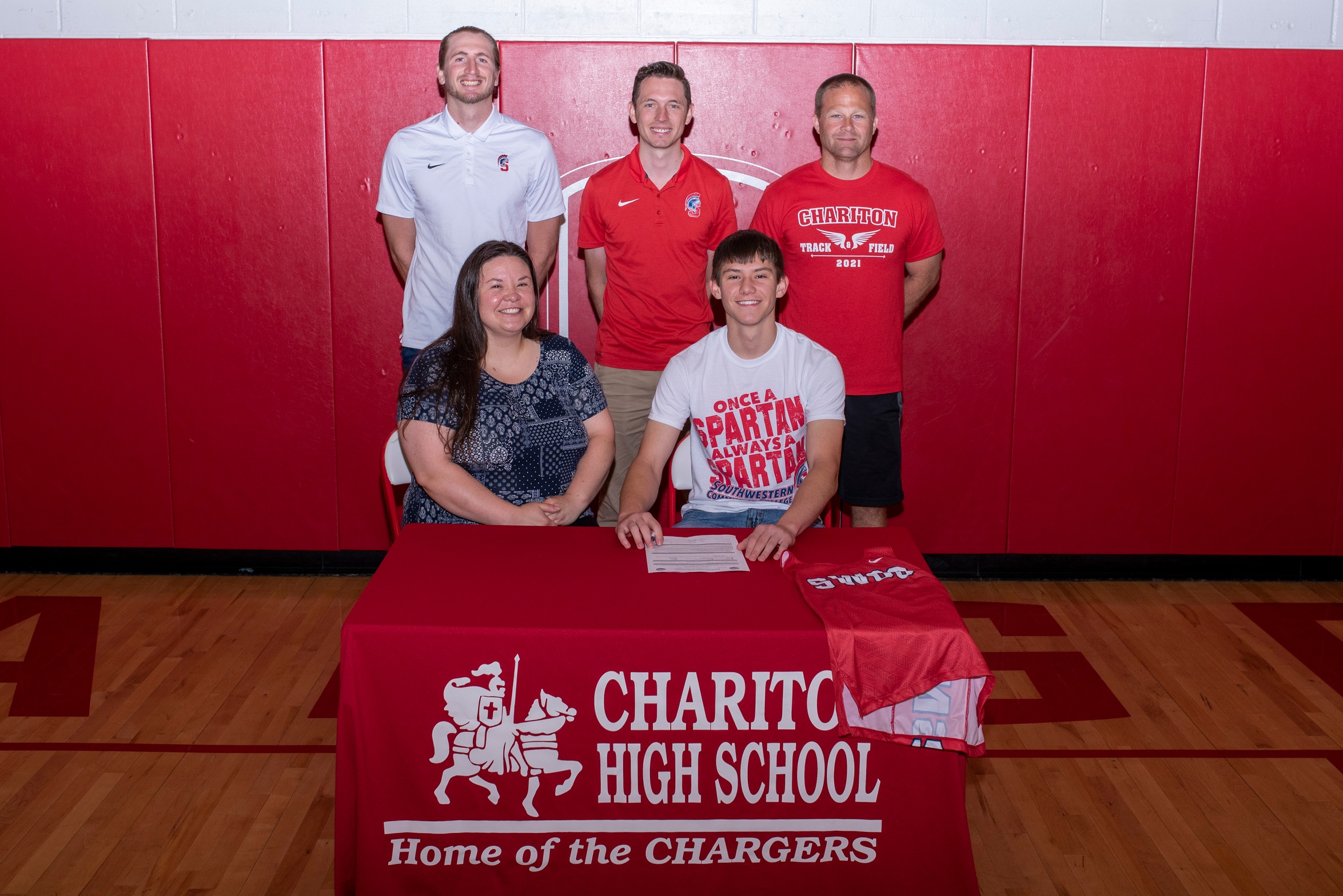 Alex Bates signs his National Letter of Intent to join the Southwestern track and field program. He is joined, in front, by his mother, Abby. Pictured in back, from left, are Southwestern coaches Jackson Shantz and Scott Vicker, and Chariton Track Coach Josh Snook.